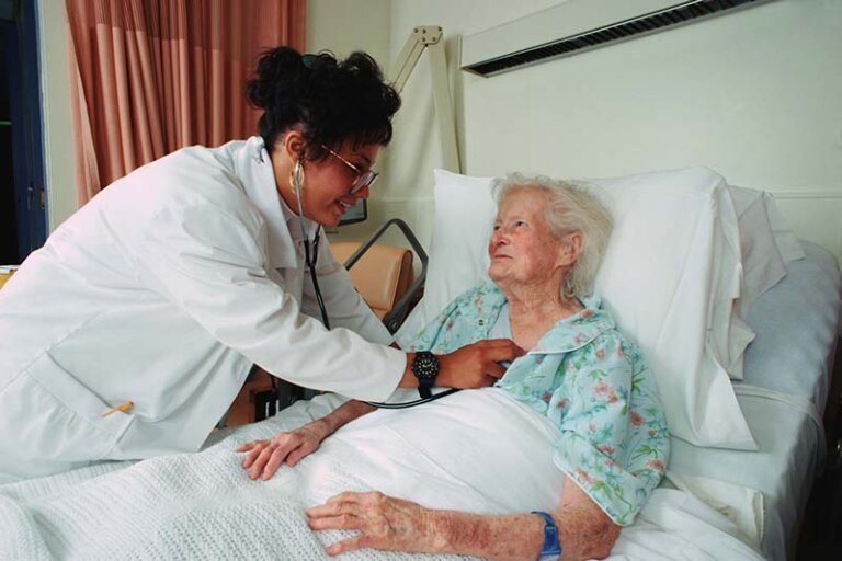 Elderly woman getting a checkup from a doctor holding a stethoscope