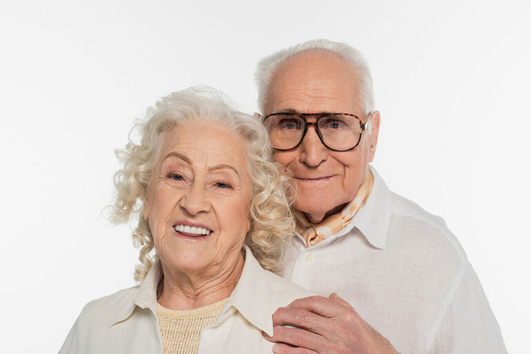 Elderly couple smiling towards a camera