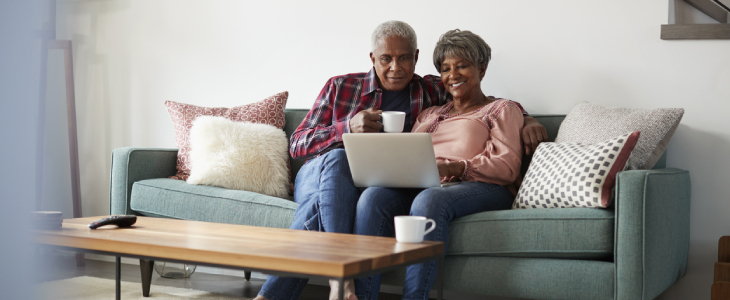 older couple sitting on couch looking at laptop