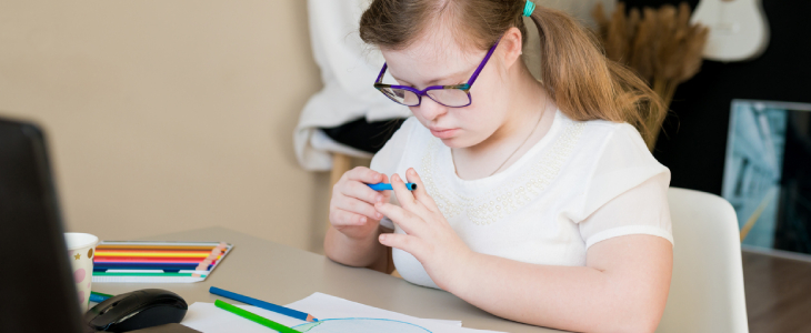 Young girl with down syndrome drawing on desk